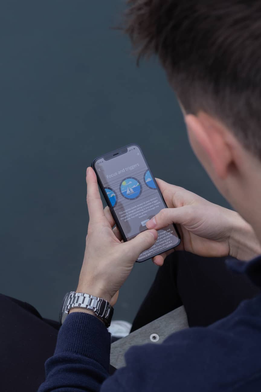 A man sitting and holding a phone with the Meta Learn app.